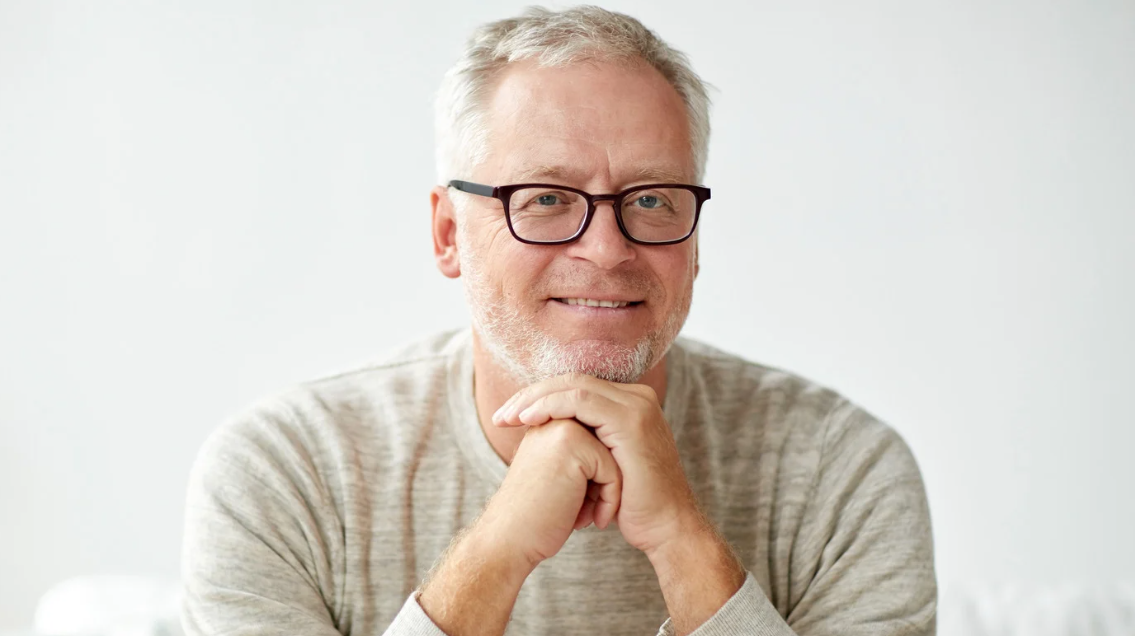 Man wearing glasses and a light sweater against a white background