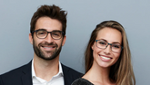 Two people wearing glasses against a gray background